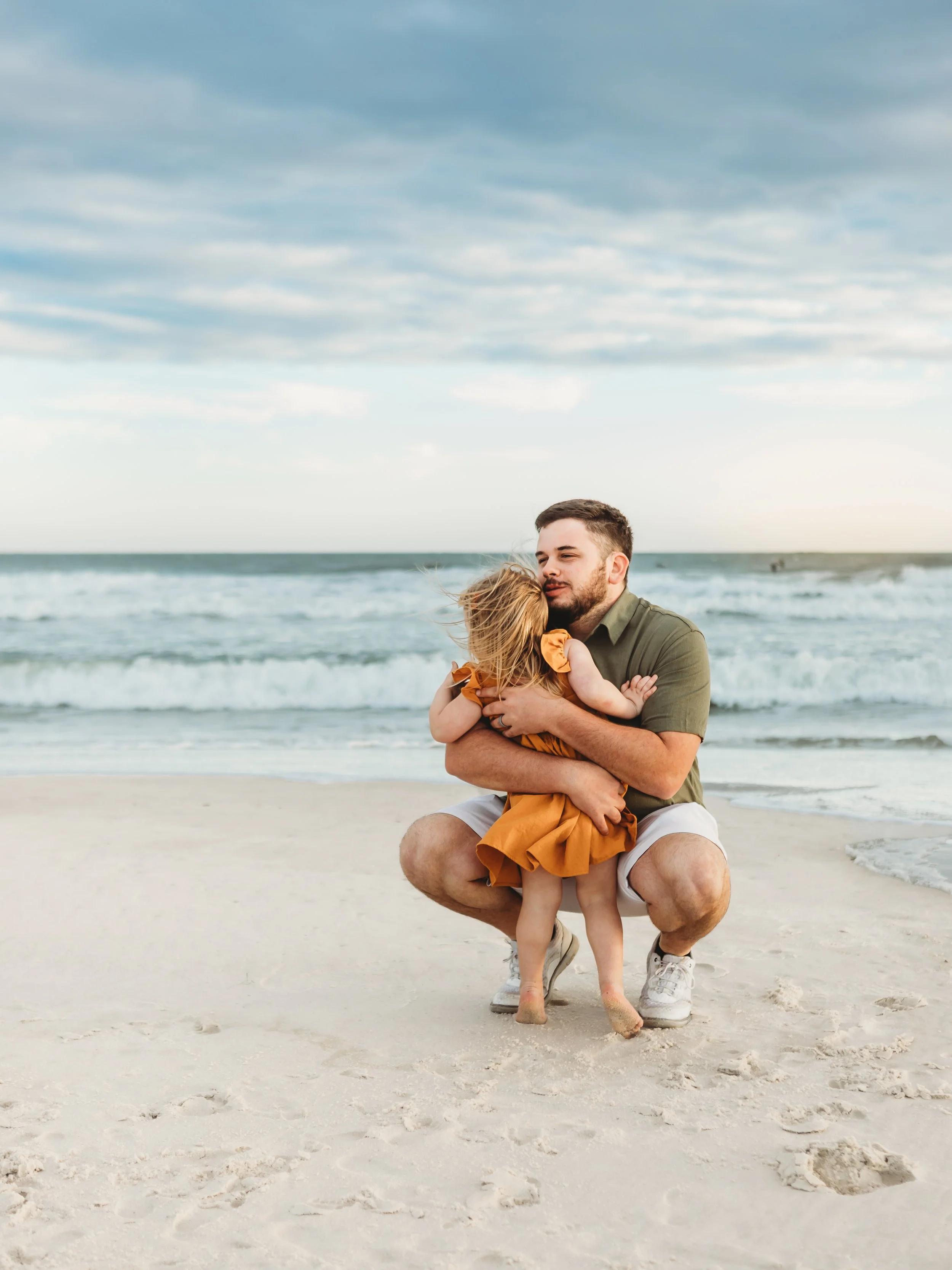 A candid beach portrait of a father and his daughter during a family session in Orange Beach. 