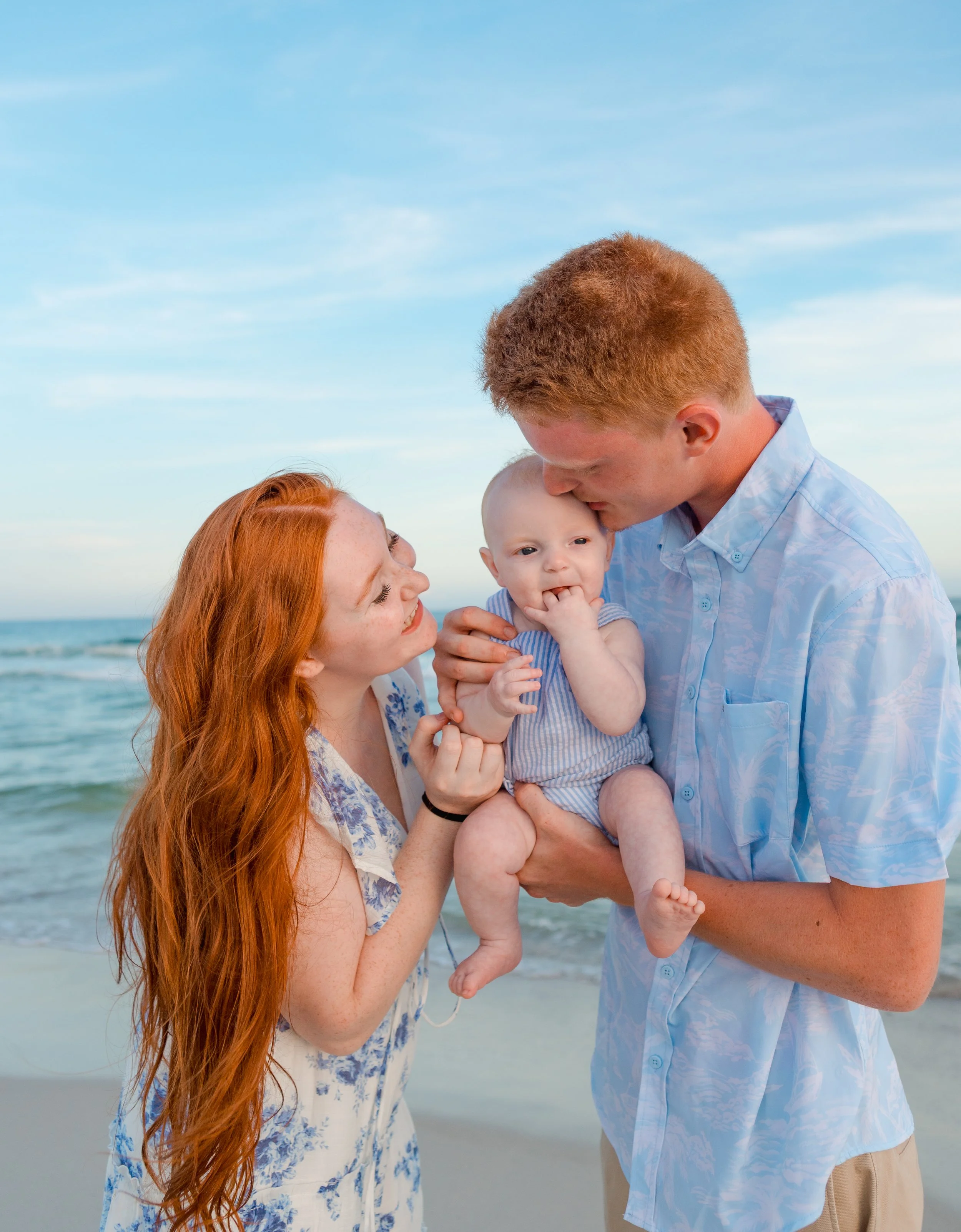 mom, dad, and baby. All red heads. At the beach, enjoying there vacation at sunset in Orange Beach, AL.