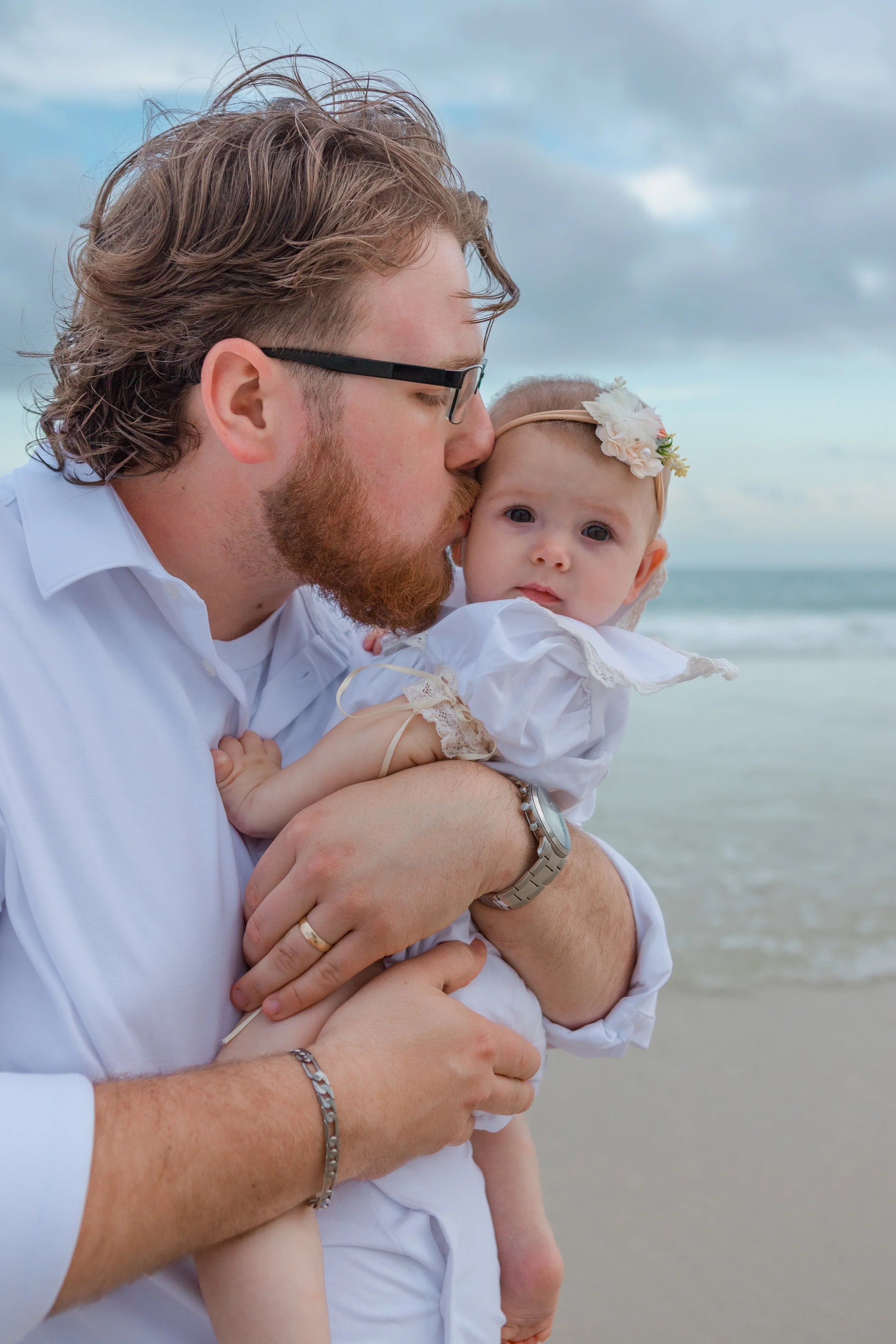 A dad kissing his baby girl at the beach on the gulf coast while on vacation 