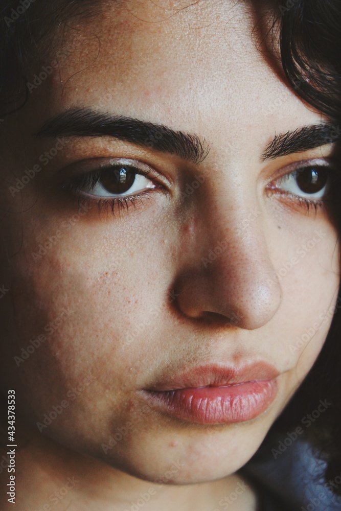 Close-up of a woman's face showing her dark eyebrows, brown eyes, and lips.