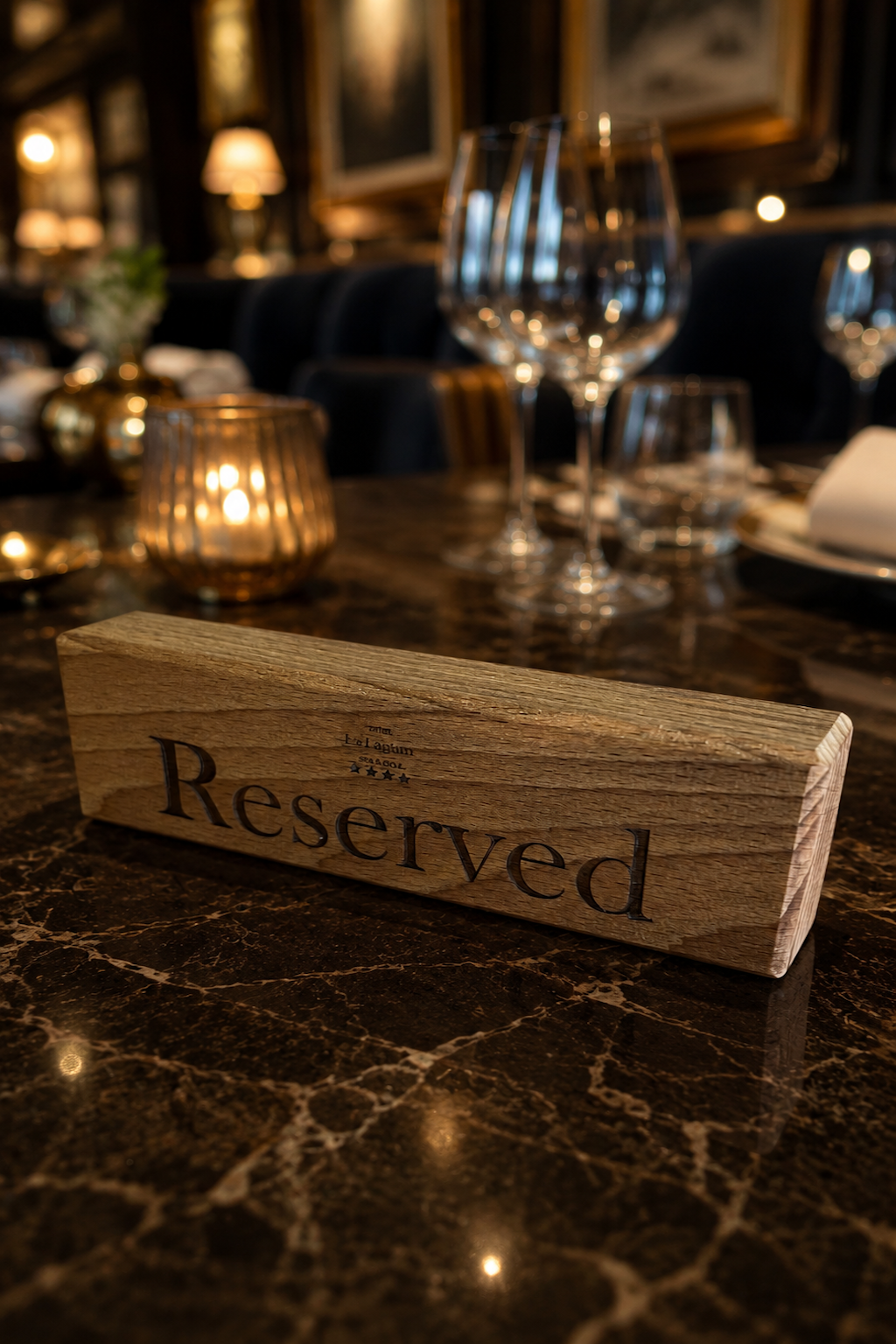 Wooden 'Reserved' sign on a dark marble table in an elegant restaurant setting with wine glasses and warm lighting.