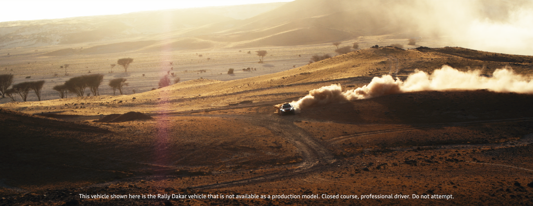 Ein Geländewagen fährt auf einer staubigen, hügeligen Landschaft und wirbelt Staub auf, im Sonnenlicht.