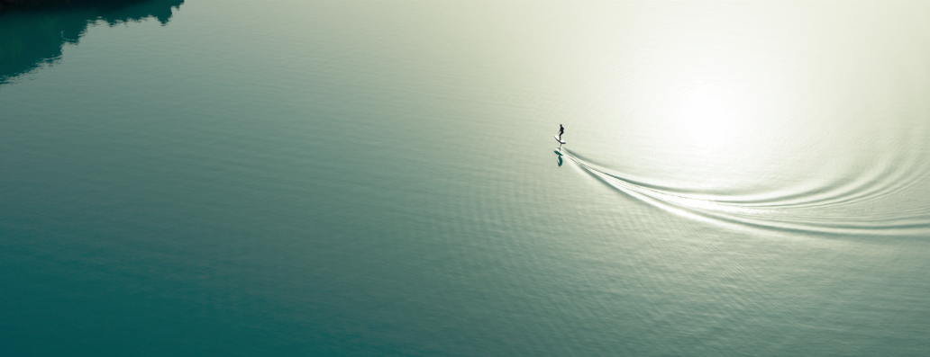 Ein kleines Motorboot mit einer Person, die auf einem ruhigen See fährt, umgeben von Bäumen.