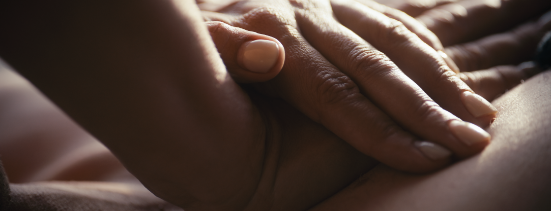 Nahaufnahme von einer Hand, die auf eine andere Hand aufliegt.