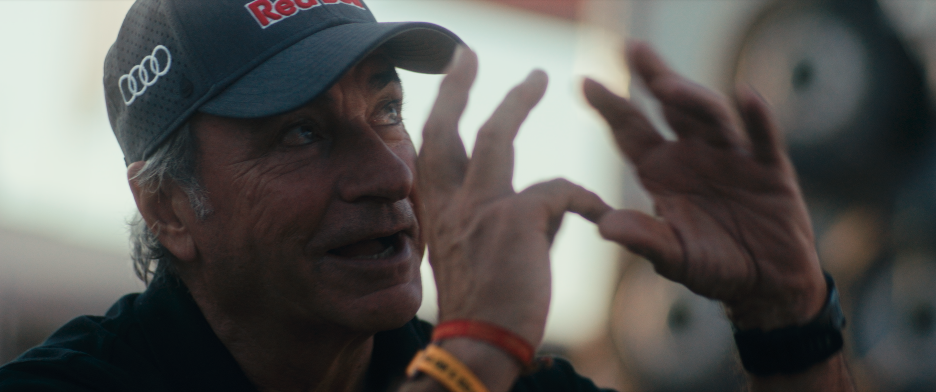 Mann in einem Audi- und Red Bull-Baseball-Cap spricht begeistert und macht eine Handgeste.