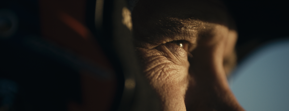 Nahaufnahme eines Mannes mit Helm, Blick nach rechts, im automobilen Umfeld.