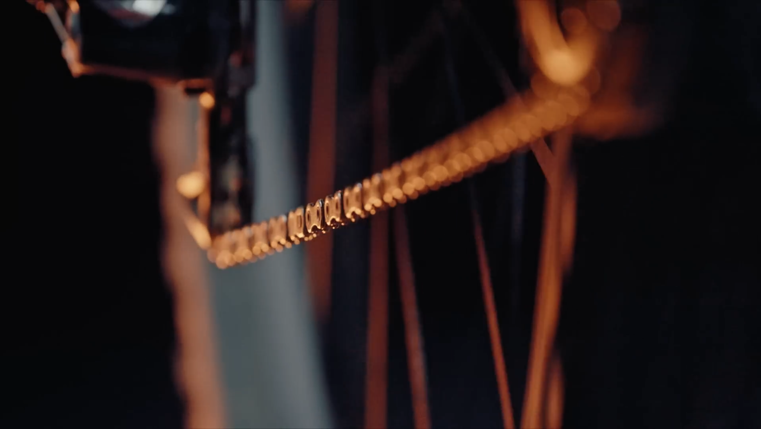 Nahaufnahme einer Kette, die an einer Gitarre hängt, bei warmem Licht. Im Hintergrund sind Gitarrensaiten sichtbar.