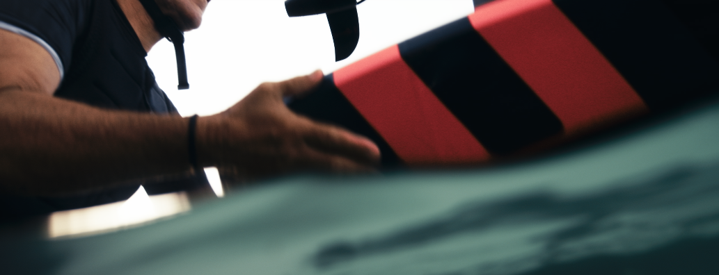 Ein Mensch hält ein schwarzes Gerät, möglicherweise eine Kamera, während er ein rotes und schwarzes Objekt berührt.