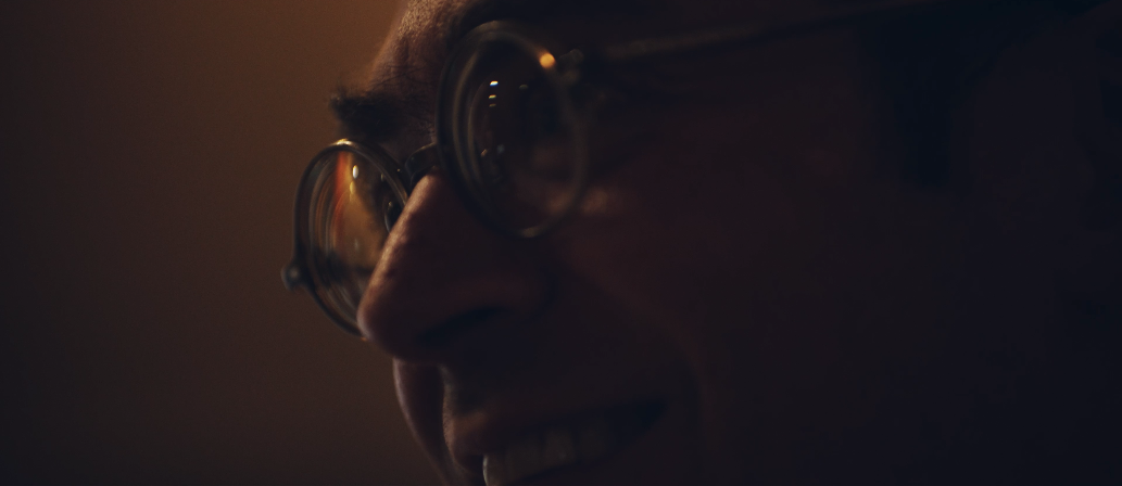 Nahaufnahme einer älteren Person mit Brille, die lächelt.