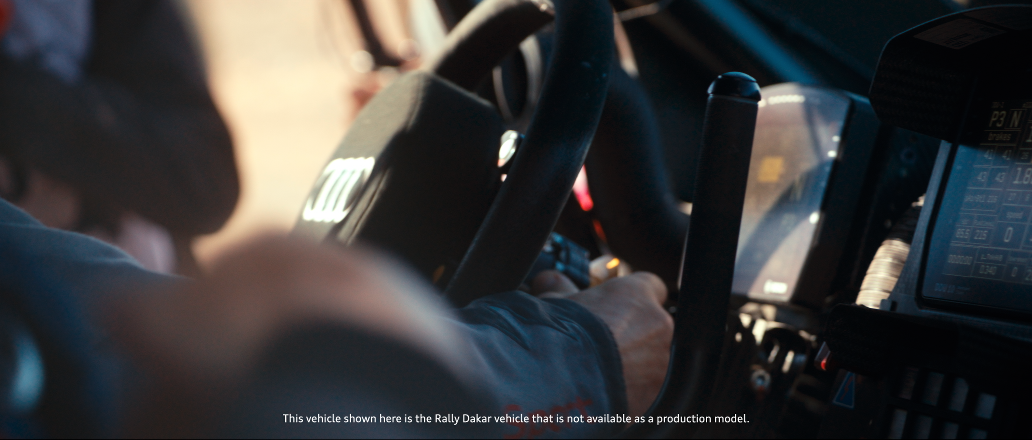 Das Innere eines LKW-Fahrzeugs mit dem Lenkrad und Fahrern in einem Fahrzeug, wahrscheinlich im Rallye- oder Rally Dakar-Kontext.