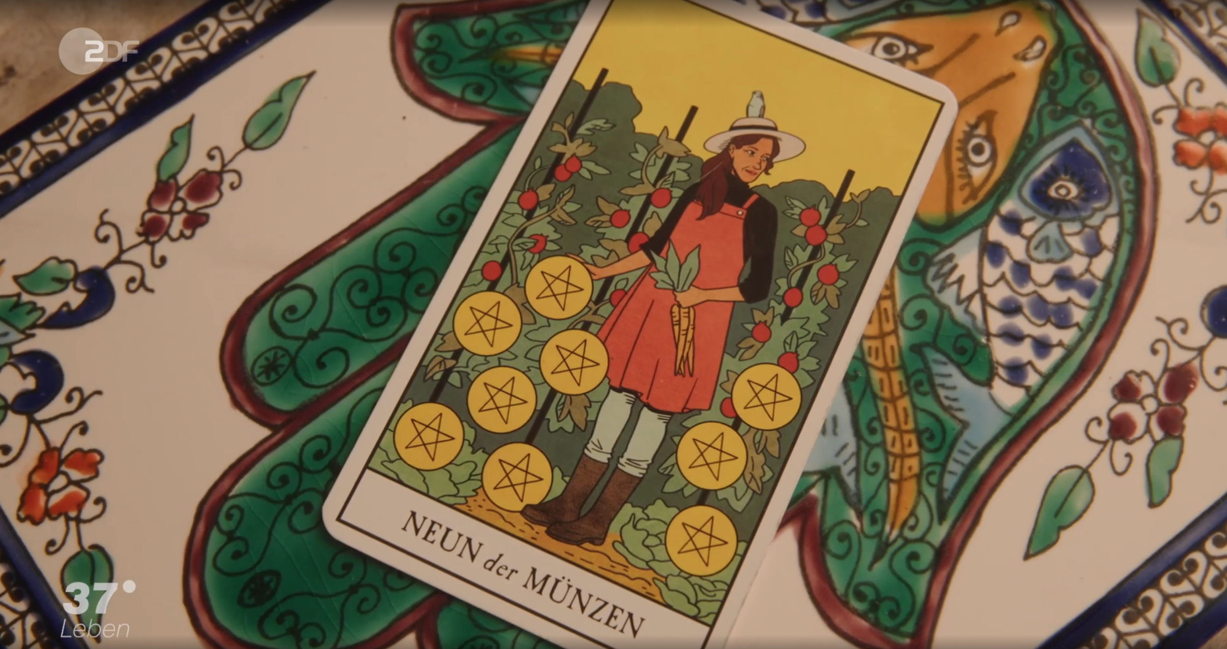 Tarotkarte mit einem Bauern, der umgeben ist von 9 Münzen und der Aufschrift 'NEUN der MÜNZEN'.
