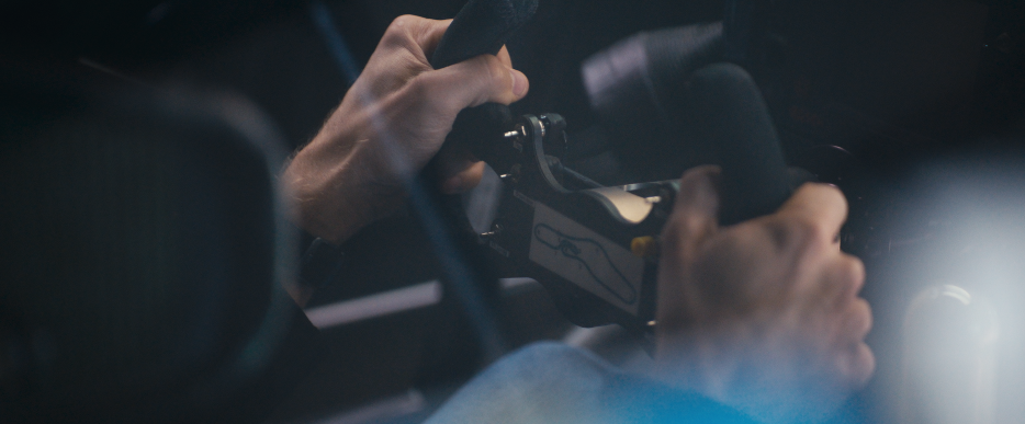 Nahaufnahme von Händen, die ein Lenkrad und Schalthebel in einem Auto halten.