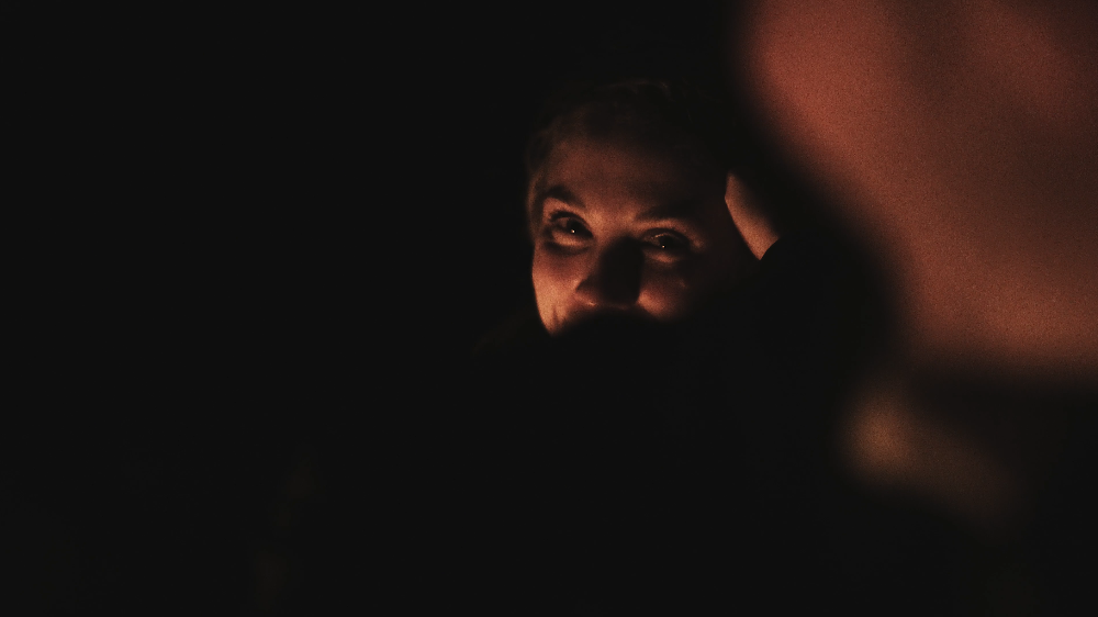 Nahaufnahme eines lachenden Mannes im Dunkeln mit einem Licht, das nur sein Gesicht beleuchtet.