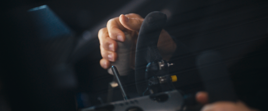 Nahaufnahme einer Hand, die eine Automobilsteuerung oder ein Lenkrad in einem Fahrzeug hält.