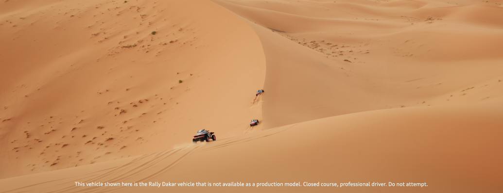 Drei Allradfahrzeuge in einer Sandwüste, die in einer Reihe fahren, mit hohen Sanddünen im Hintergrund.