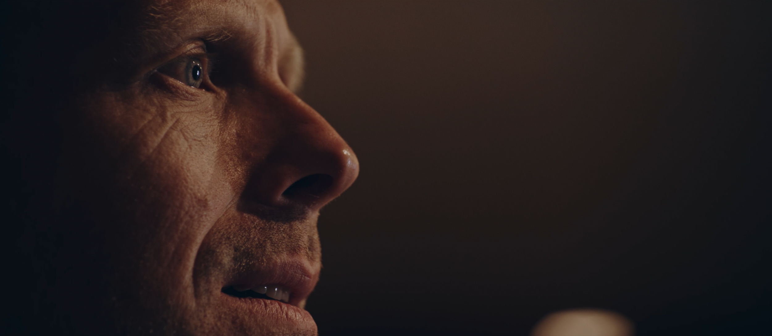 Nahaufnahme eines Mannes, der nachdenklich schaut, mit fokussiertem Blick und im Hintergrund verschwommenen Lichtreflexen.