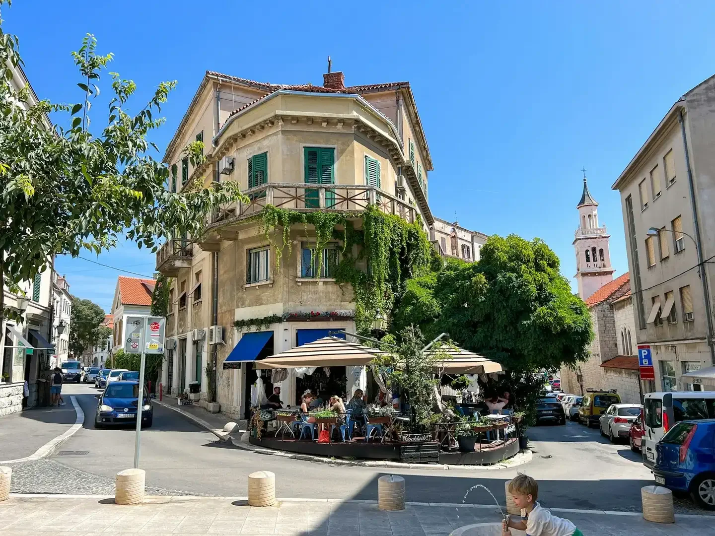 Outdoor street café in the historic centre of Split, Croatia, set beside a traditional Mediterranean building with green shutters and climbing plants.