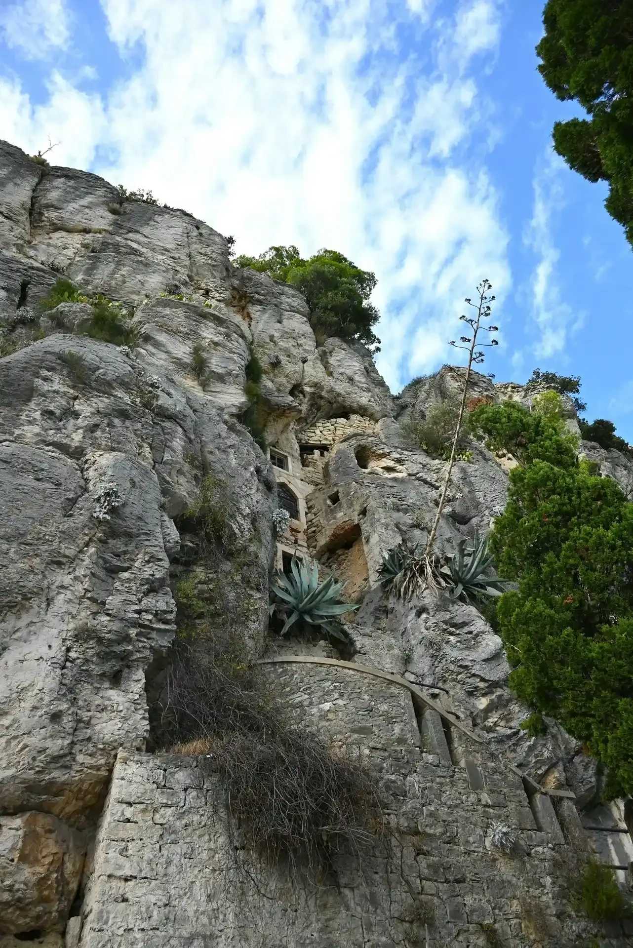 Stone hermitage built into the rocky cliffs of Marjan Hill in Split, Croatia, surrounded by Mediterranean vegetation and limestone rock formations.