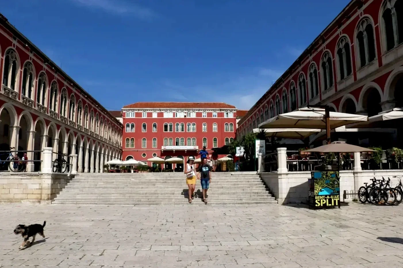 Prokurative (Republic Square) in Split, Croatia, featuring stone steps, arcaded buildings, and the historic red façade overlooking the square.