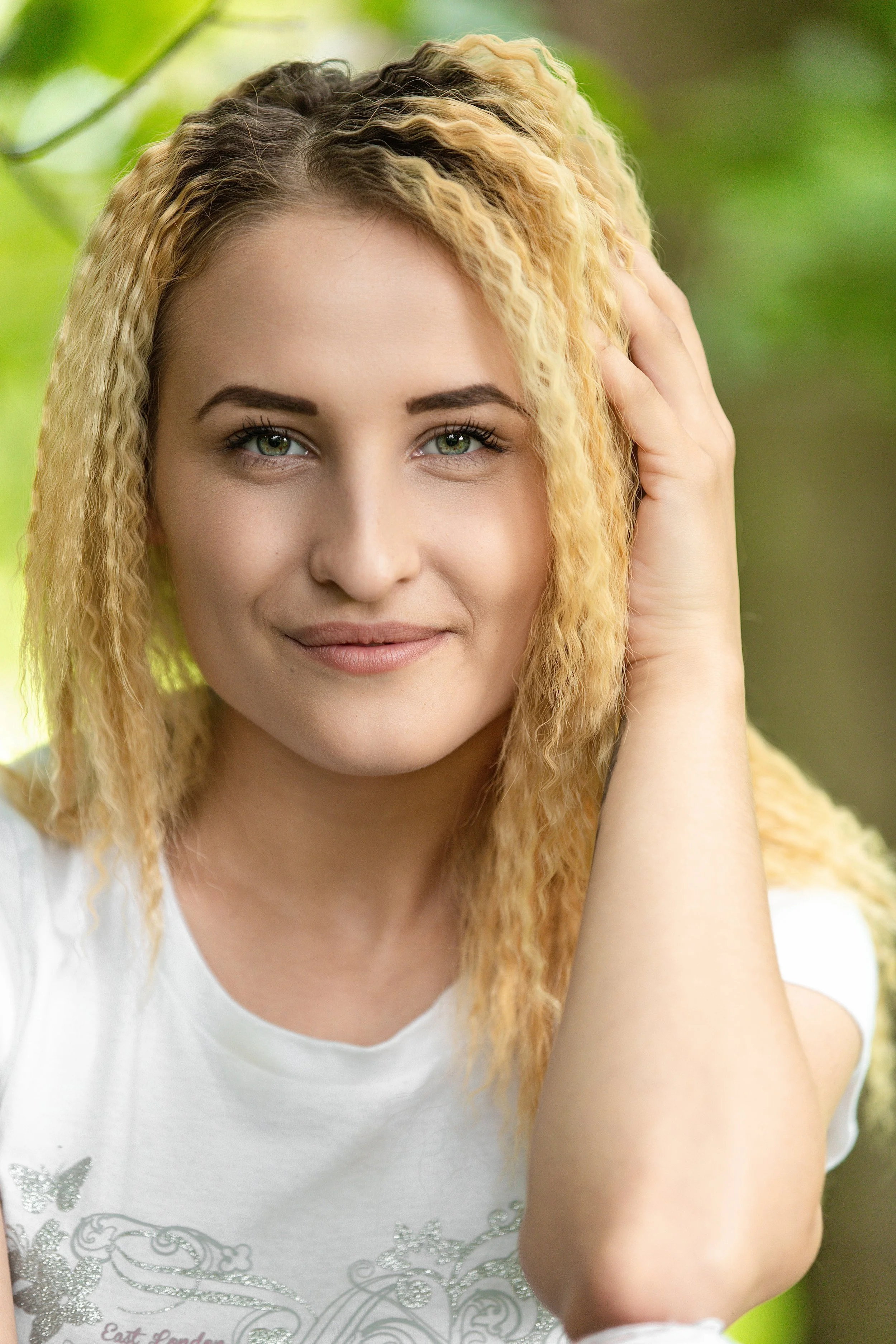 Head shot of a smiling blonde girl in the forest in the spring