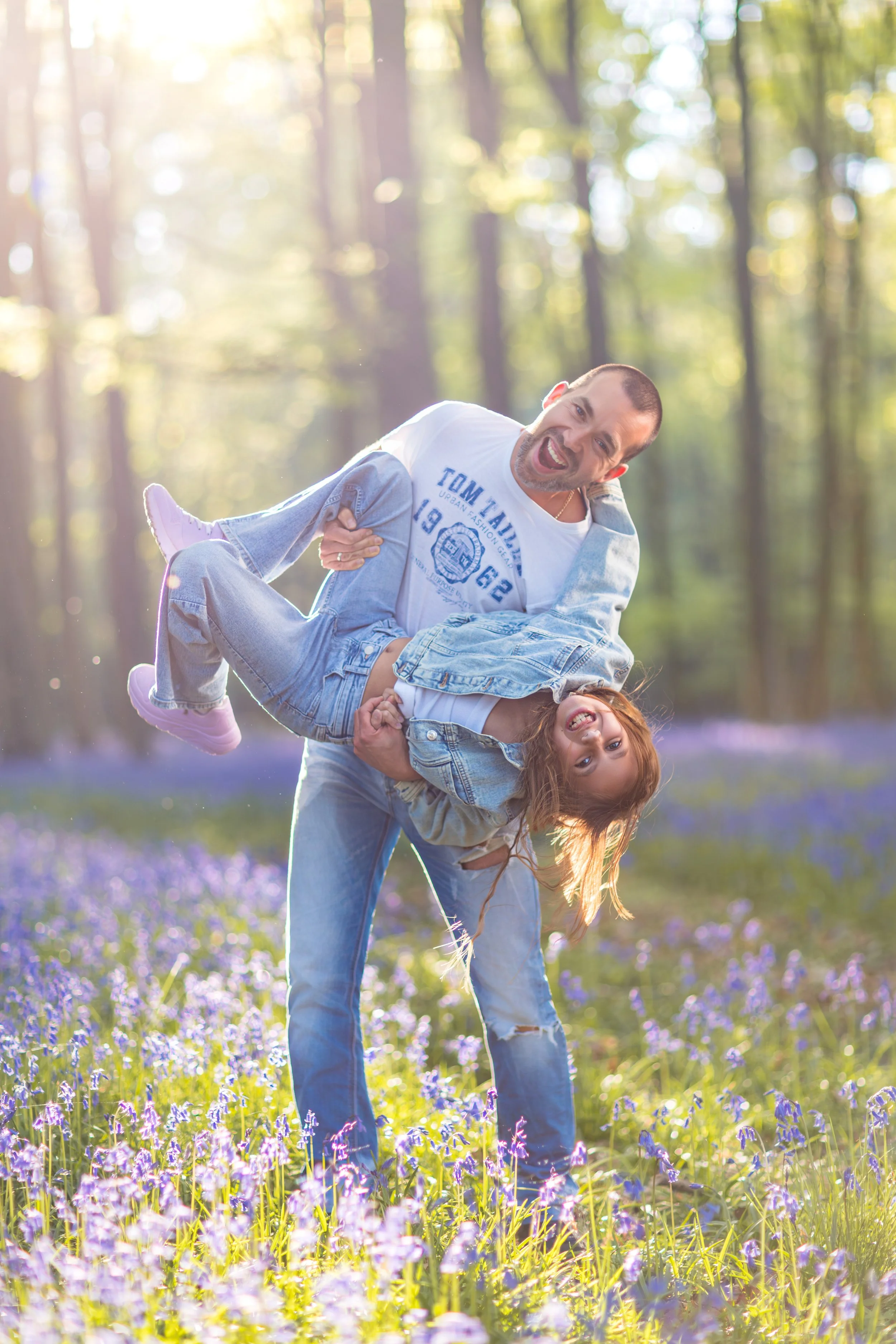 Dad and daughter fooling around in a forest covered in bluebell