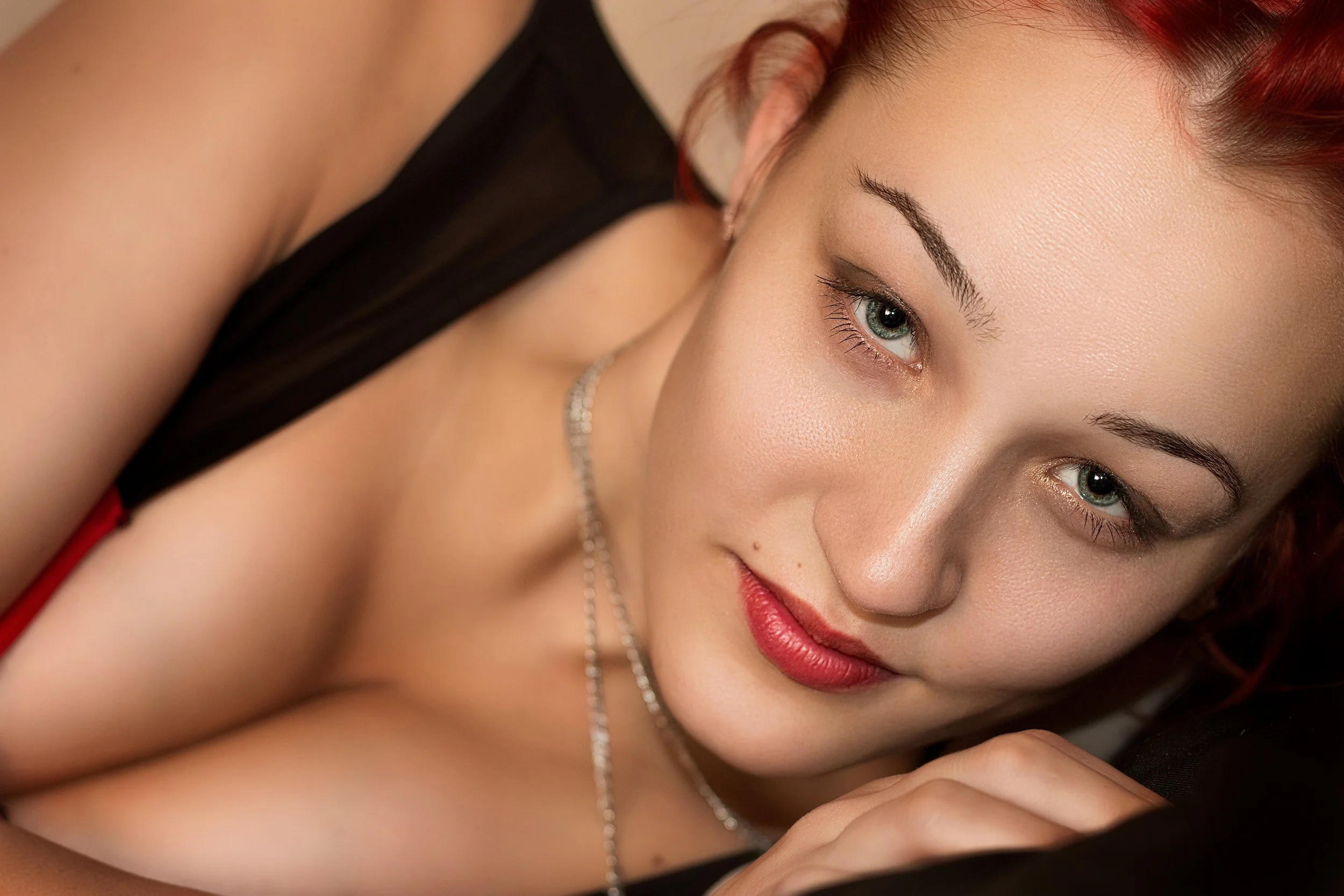 A person with red hair and bright eyes smiles warmly at the camera. The image conveys a sense of friendliness and confidence.