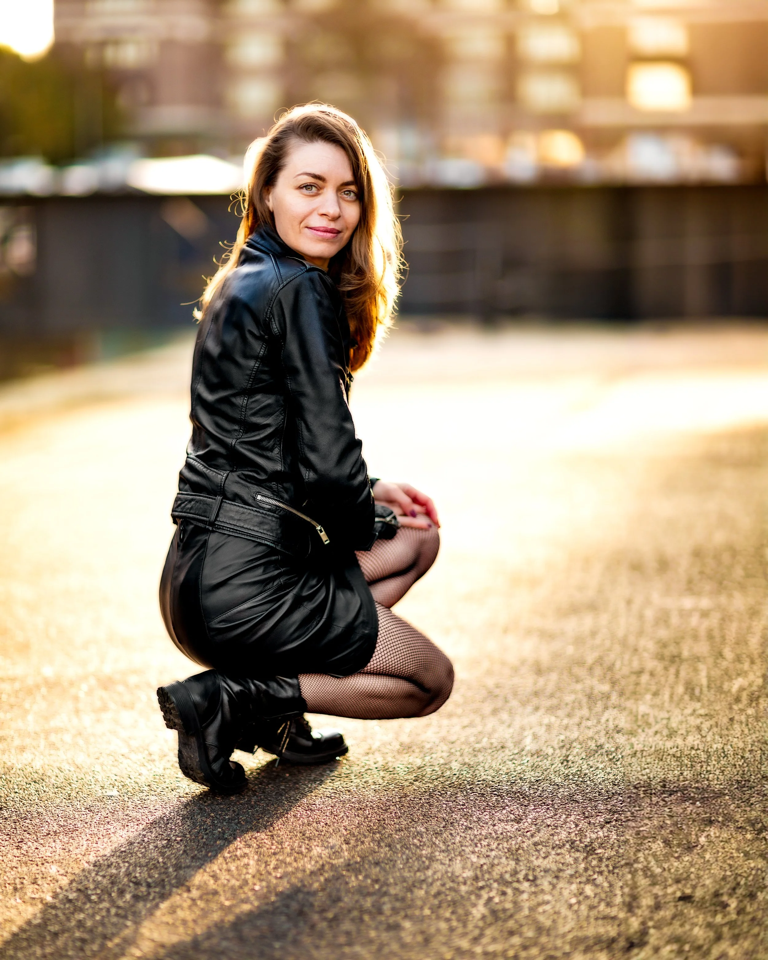 Backlit portrait of a young woman wearing leather skirt and jacket in the sunrise golden hour at Gloucester quays