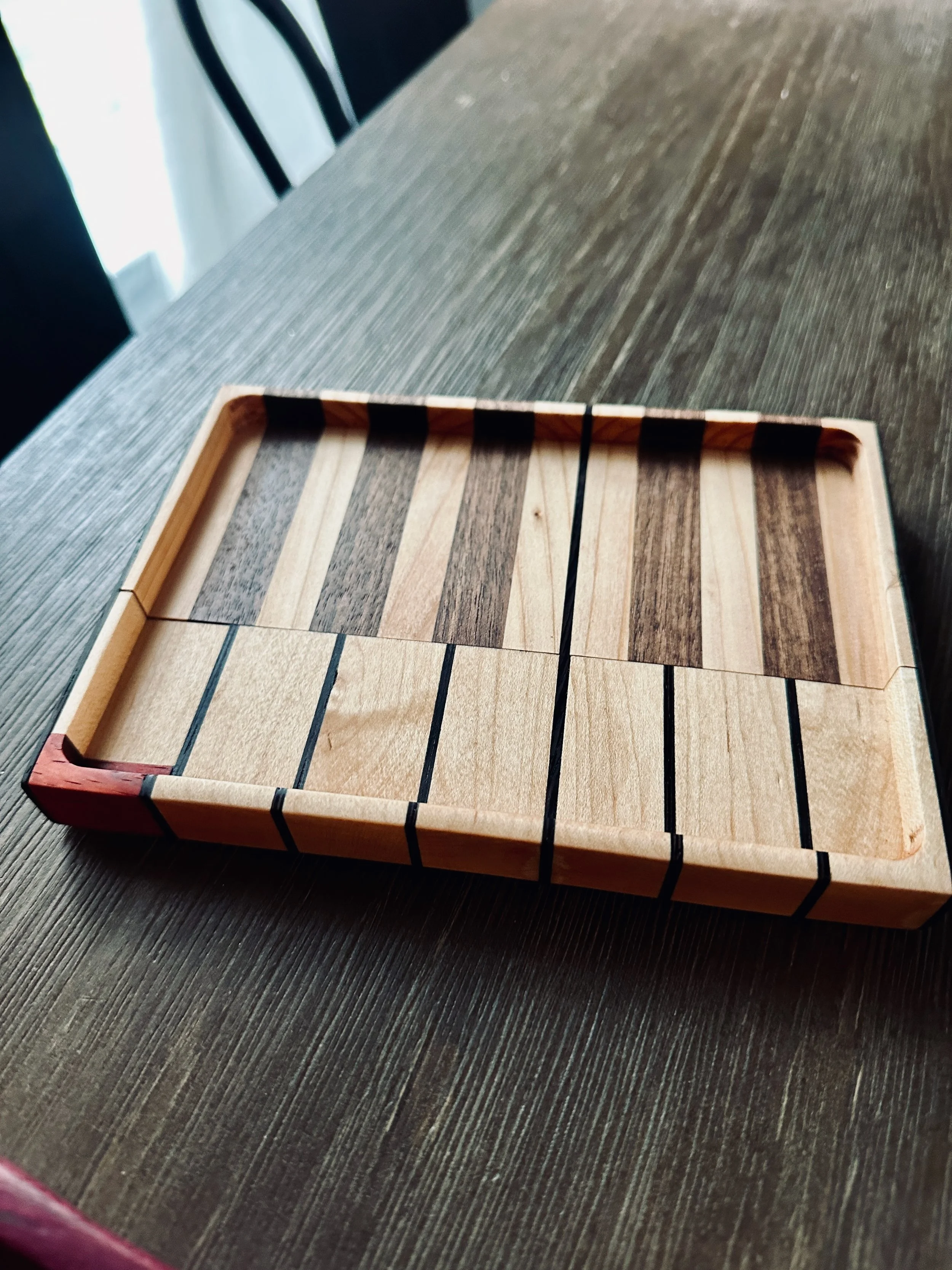 A wooden sliding tile puzzle with black lines separating different pieces, placed on a dark wooden table near a window.