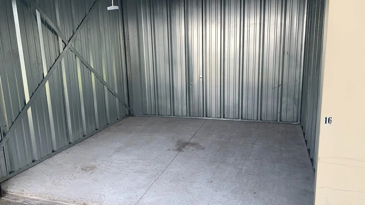 Empty parking space with gray concrete and metal walls, marked with the number 16.