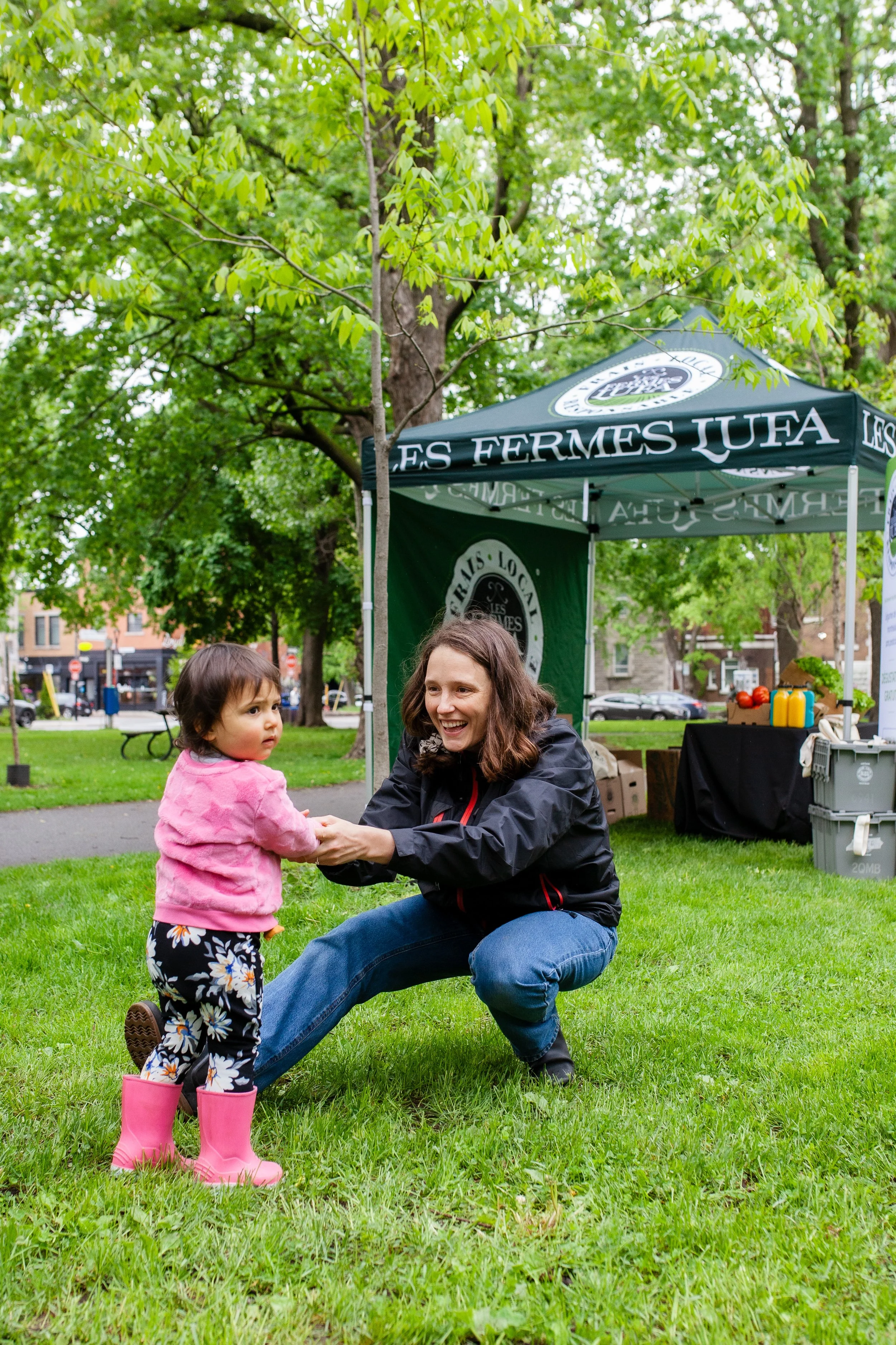 Une femme et une petite fille jouent dans un parc avec un stand en toile de fond.