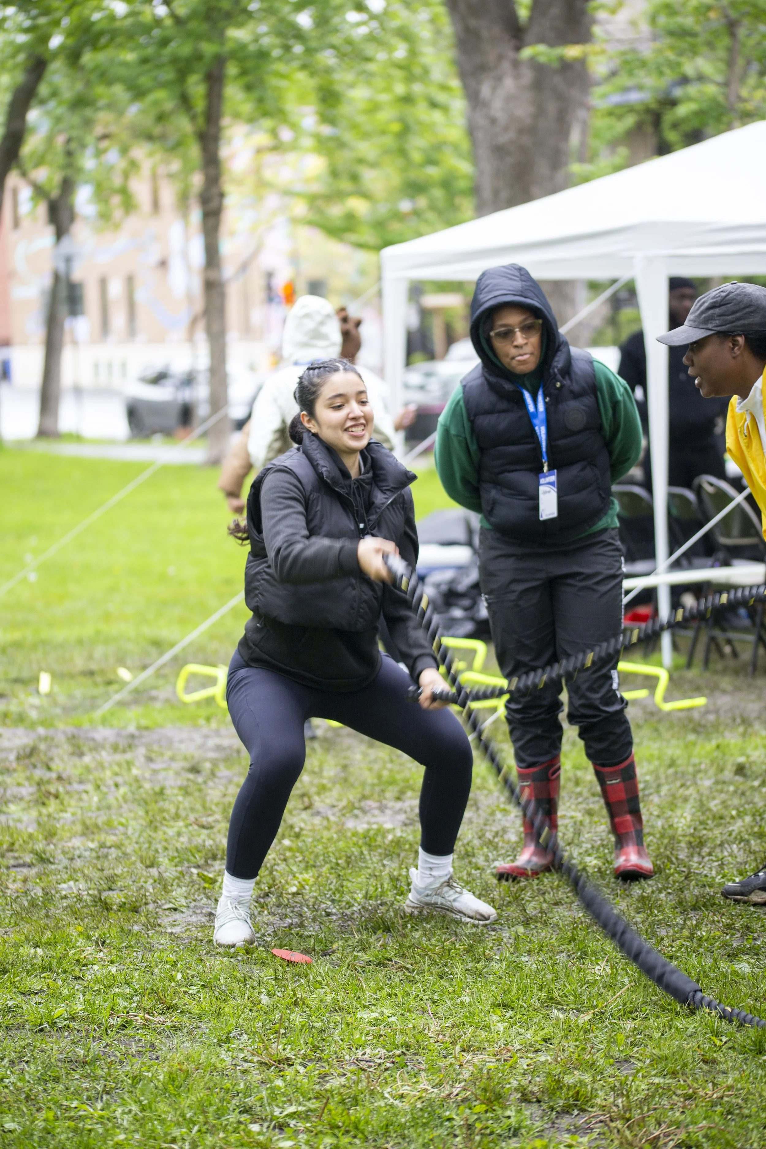 Jeune femme faisant de l'entraînement avec une corde à sauter dans un parc, entourée de personnes assistant à un événement en plein air.
