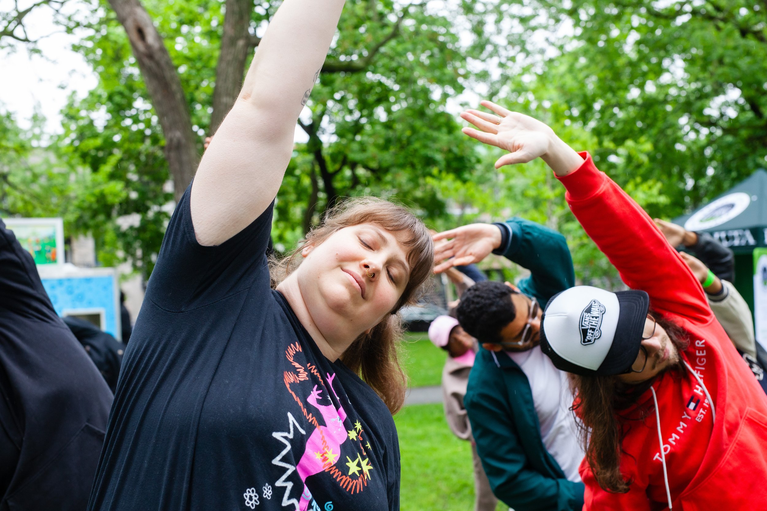 Groupe de personnes faisant du yoga ou des étirements dans un parc, entouré d'arbres verts.