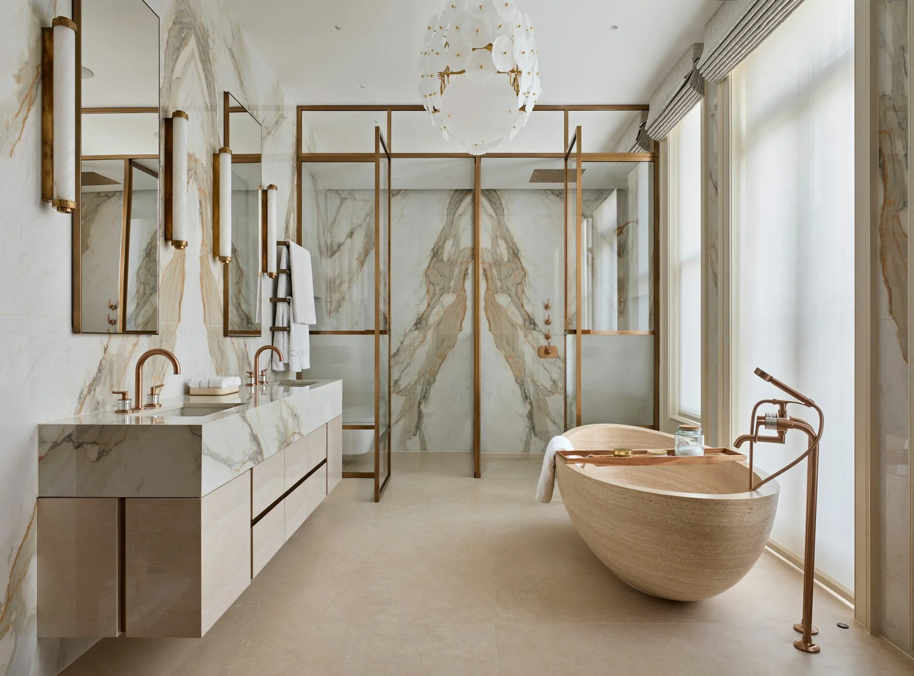 Modern bathroom with marble walls, a bathtub, double sinks, mirrors, and natural light from large windows.