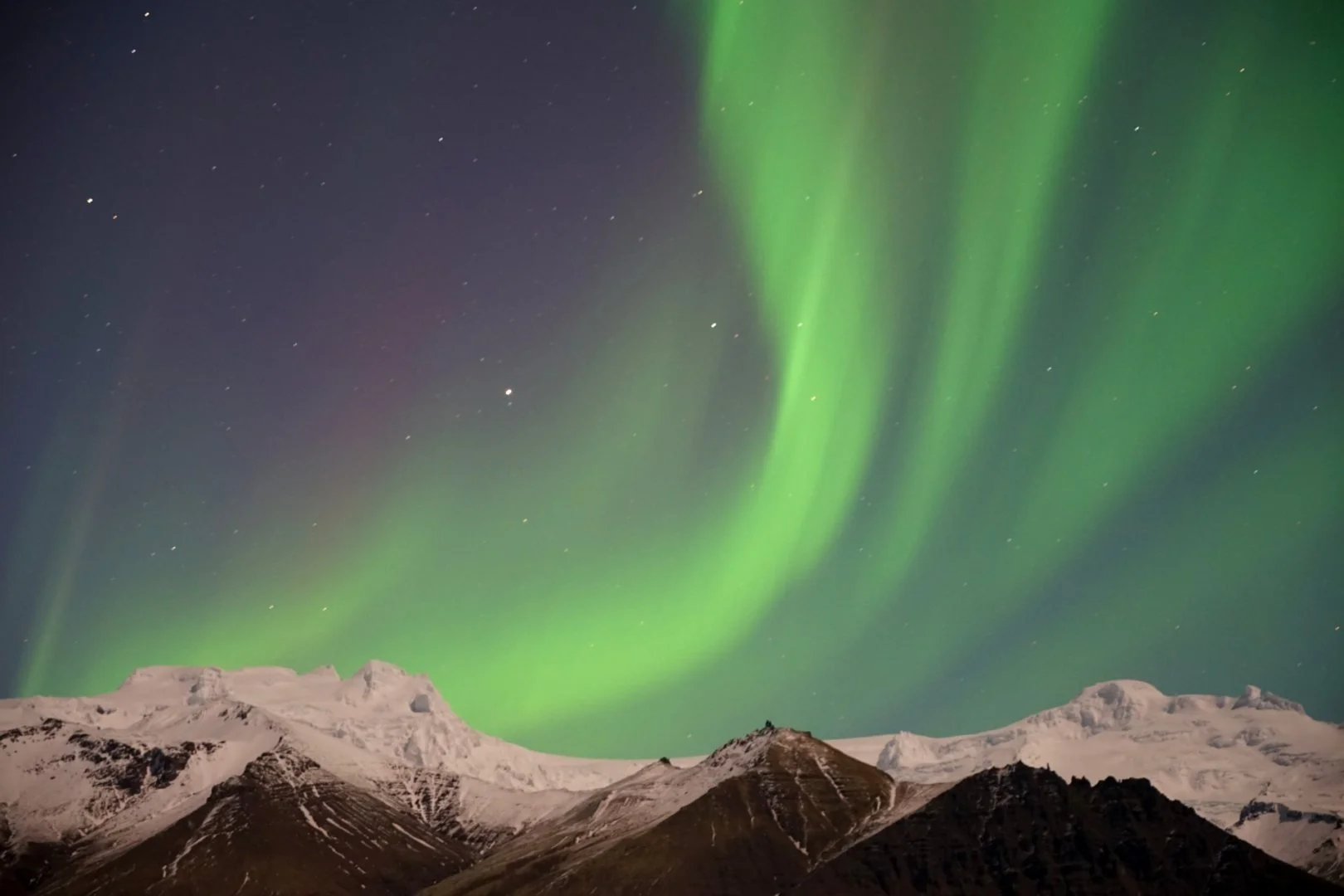Aurore boréale verte au-dessus d'un paysage de montage enneigée