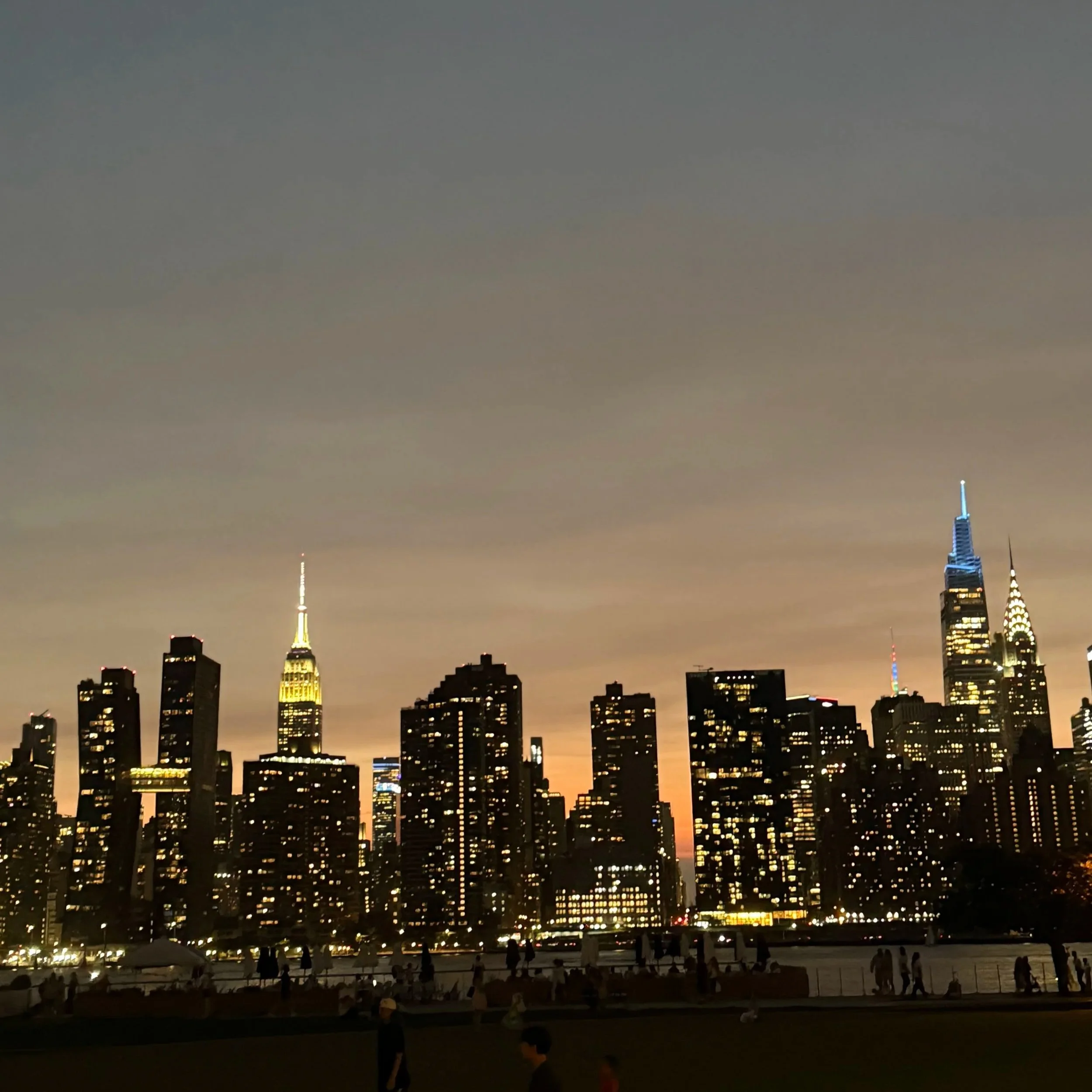 Nighttime city skyline featuring the Empire State Building and other high-rise buildings.