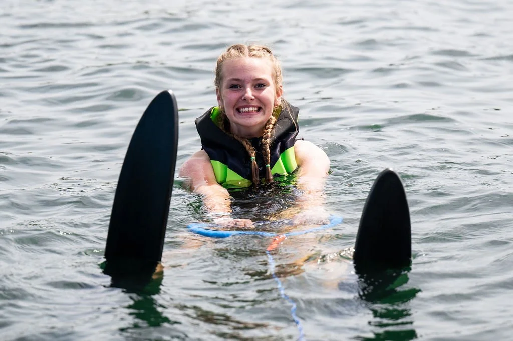young girl smiling in the water with water skis