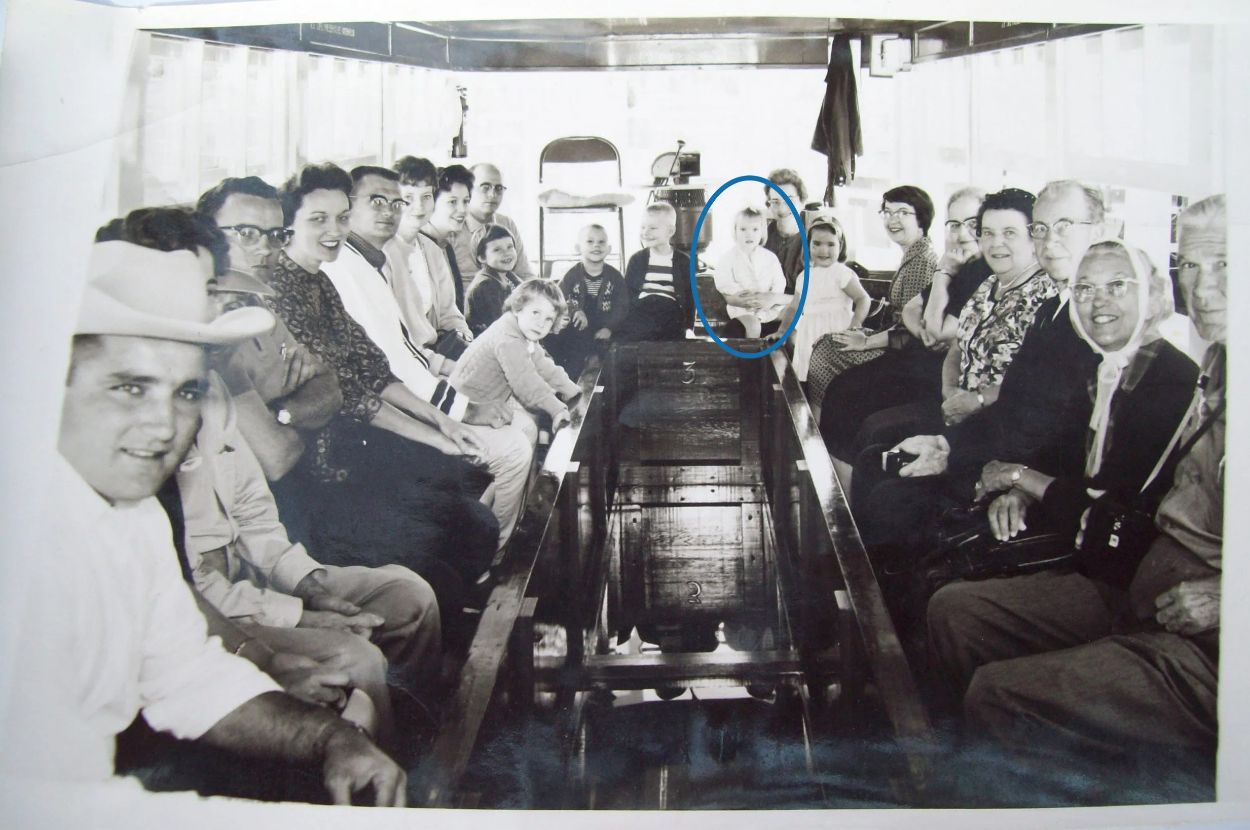 Group of adults and children seated on benches inside a glass-bottom boat at Silver Springs, with a young Karen Chadwick circled among them.