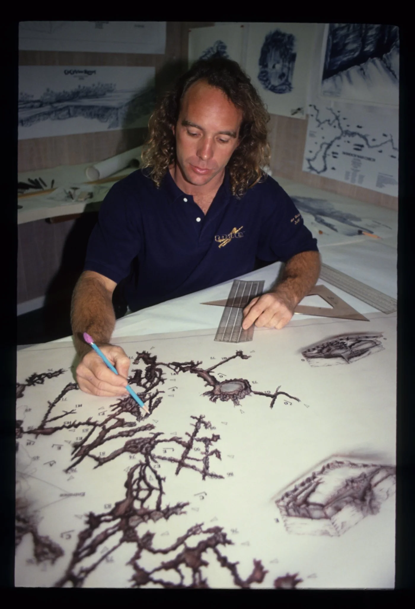 Eric Hutcheson drawing or mapping underwater cave or spring formations at a desk