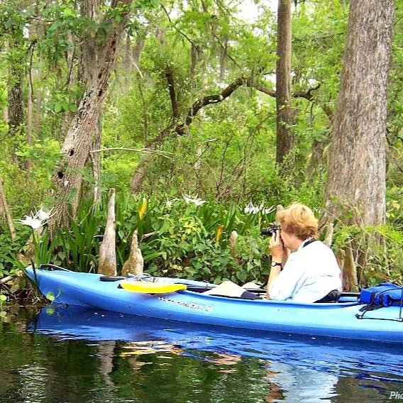Sandra Marraffino photographing from a blue kayak on the Rainbow River