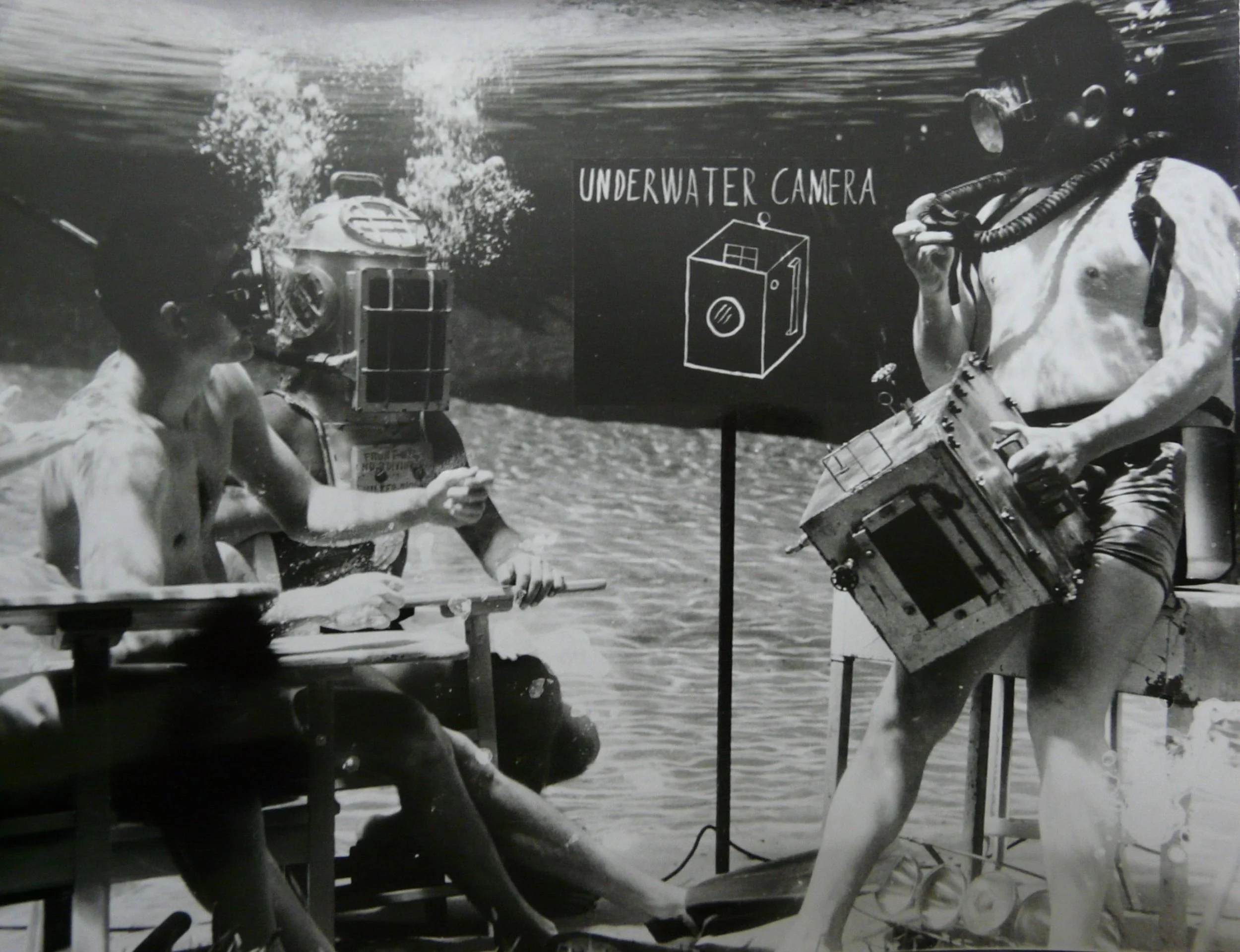 Historic black-and-white image of an early underwater filming setup in a spring