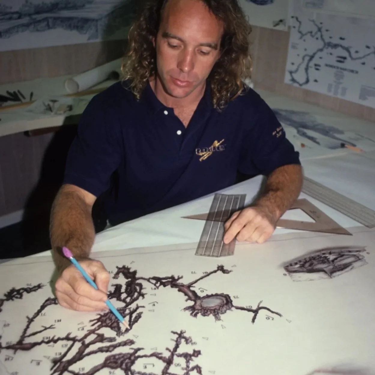 Man working at a desk drawing or mapping underwater cave or spring formations