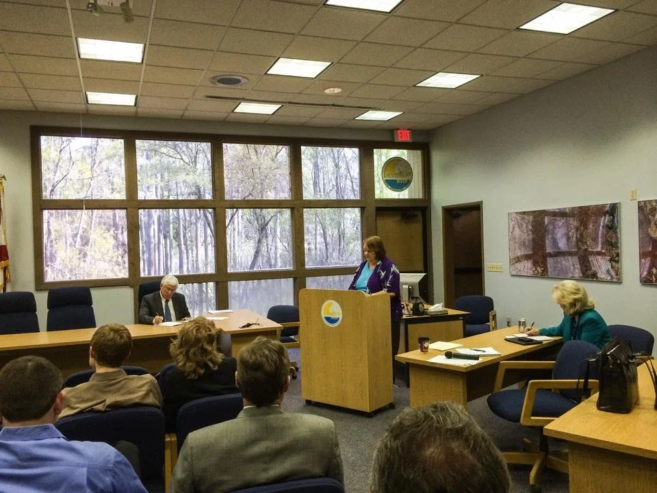 Lucinda Merritt speaking at a water management district meeting with attendees seated in the room.