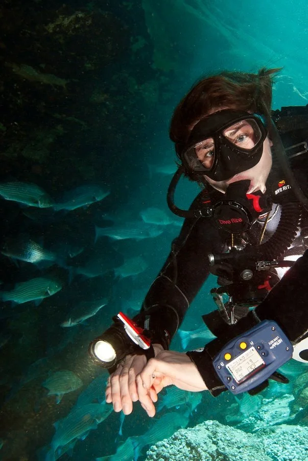 Scuba diver using underwater equipment among fish in clear spring water