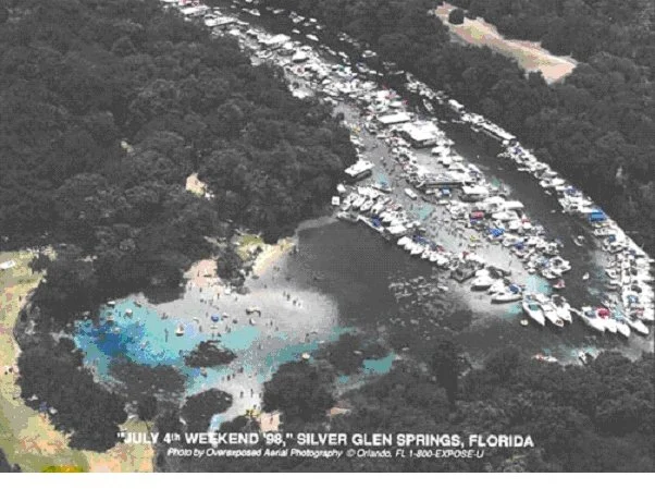 Aerial view of Silver Glen Springs crowded with boats and people along the river during a holiday weekend.