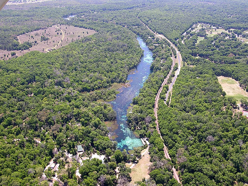 Aerial view of Rainbow Springs and Rainbow River winding through dense forest with clear blue spring water visible below