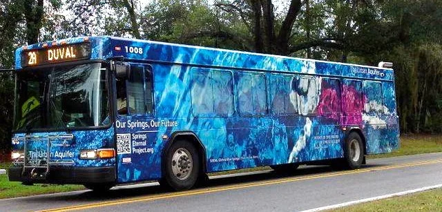 Public transit bus wrapped in underwater spring imagery, part of the Urban Aquifer SIRENA collaboration project.