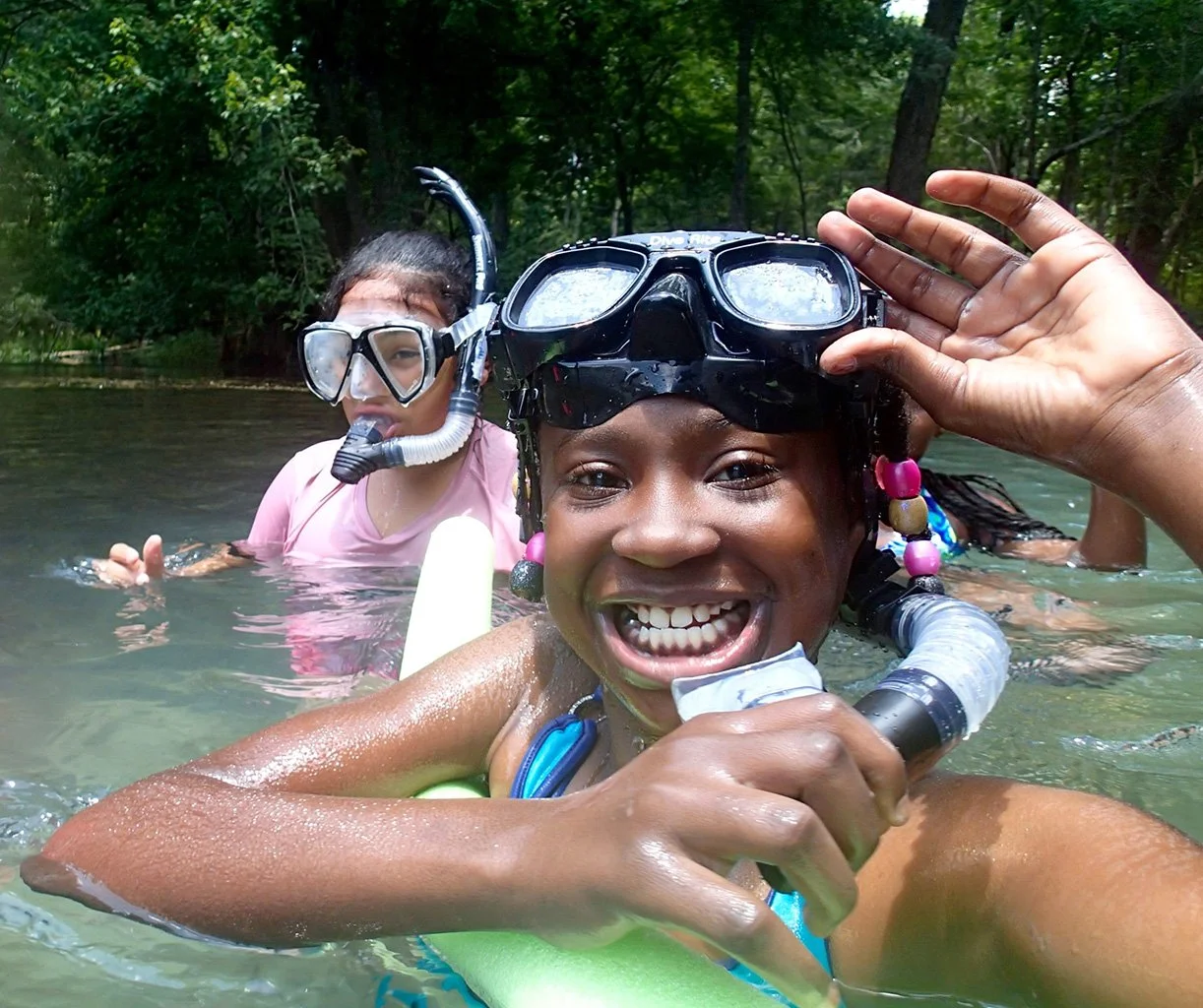 Campers in the springs with snorkeling gear on smiling at the surface.