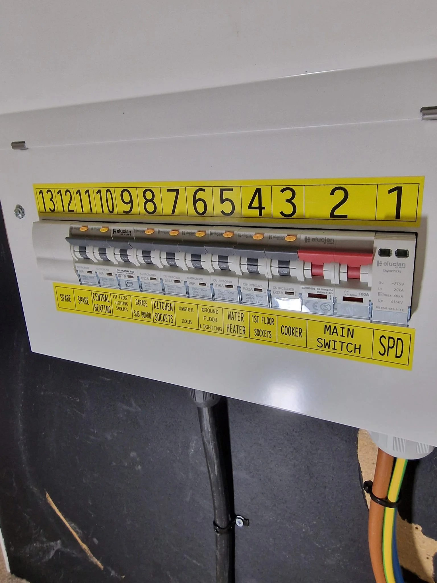 Electrical breaker box with labeled circuit switches and yellow labels indicating their functions.