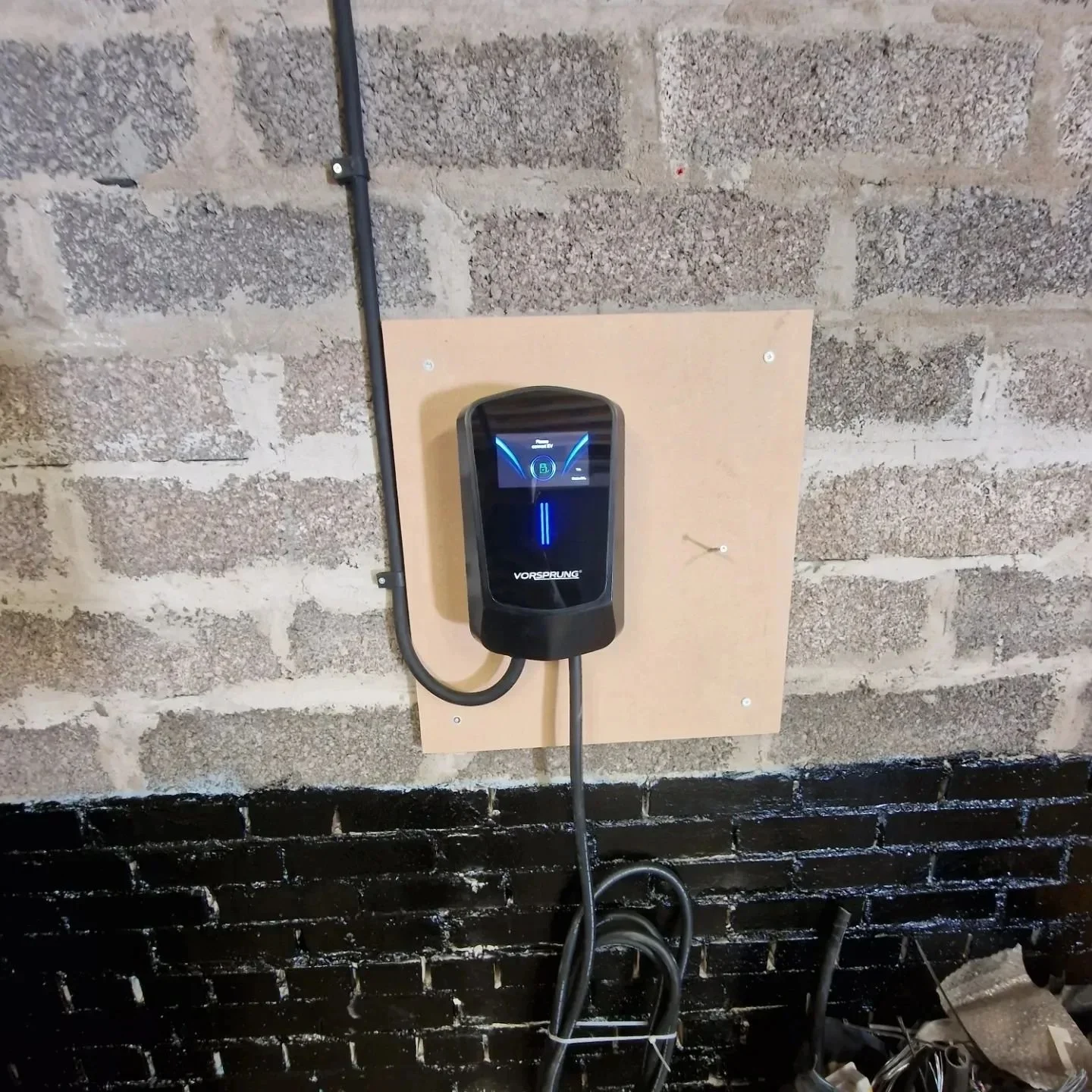 Electric vehicle charging station mounted on a brick wall.