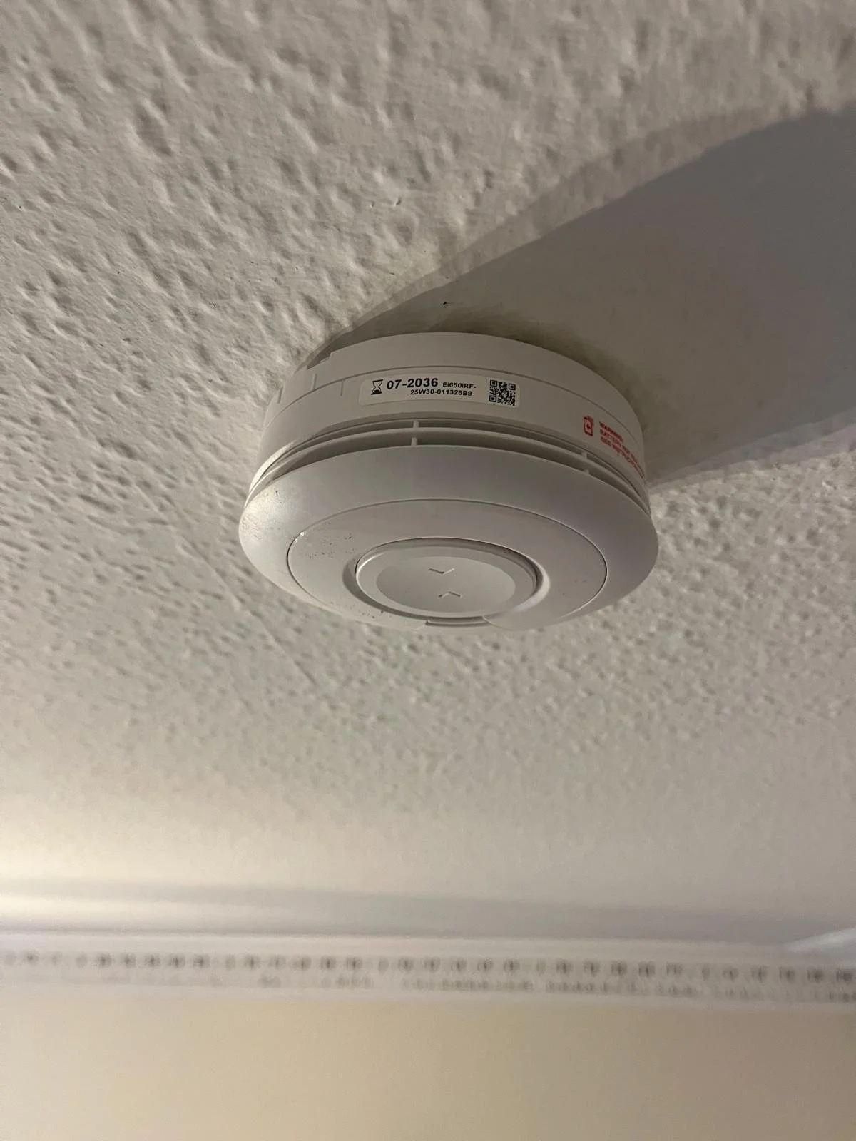A smoke detector mounted on a ceiling.